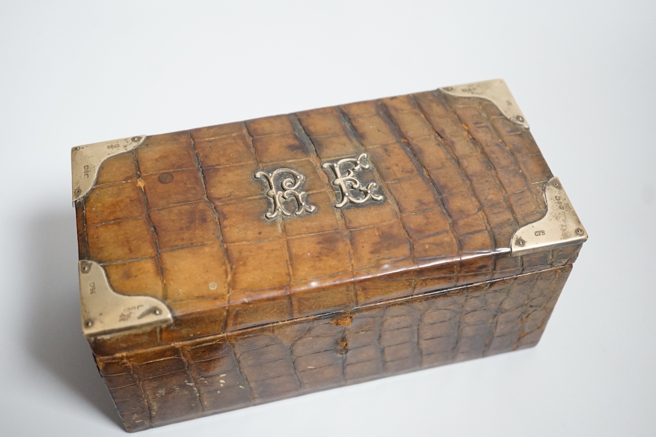 A late Victorian silver mounted crocodile skin jewellery box, 19cm and two silver and enamel mounted brushes.